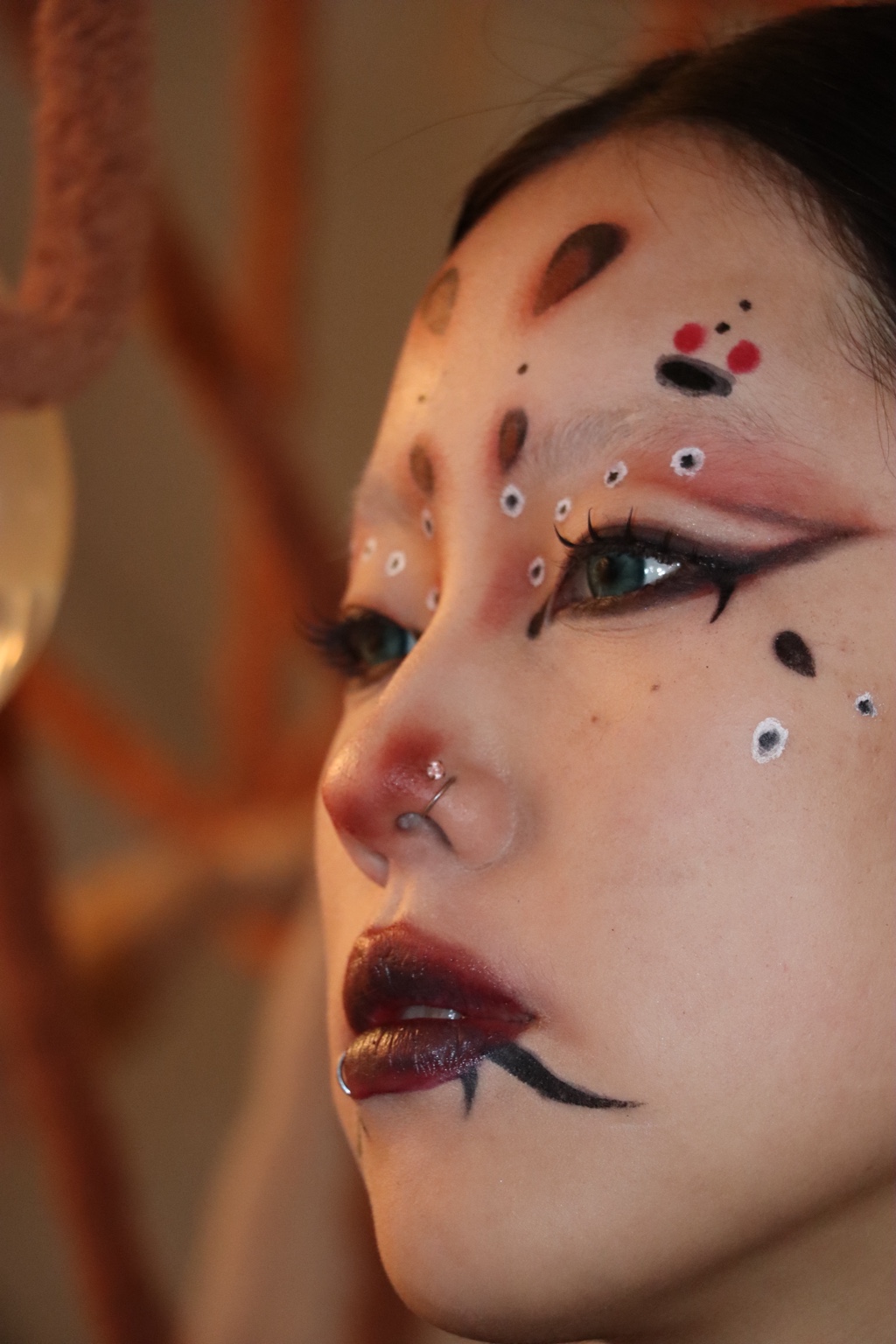 Close-up fashion portrait with graphic red, black and white makeup in warm light